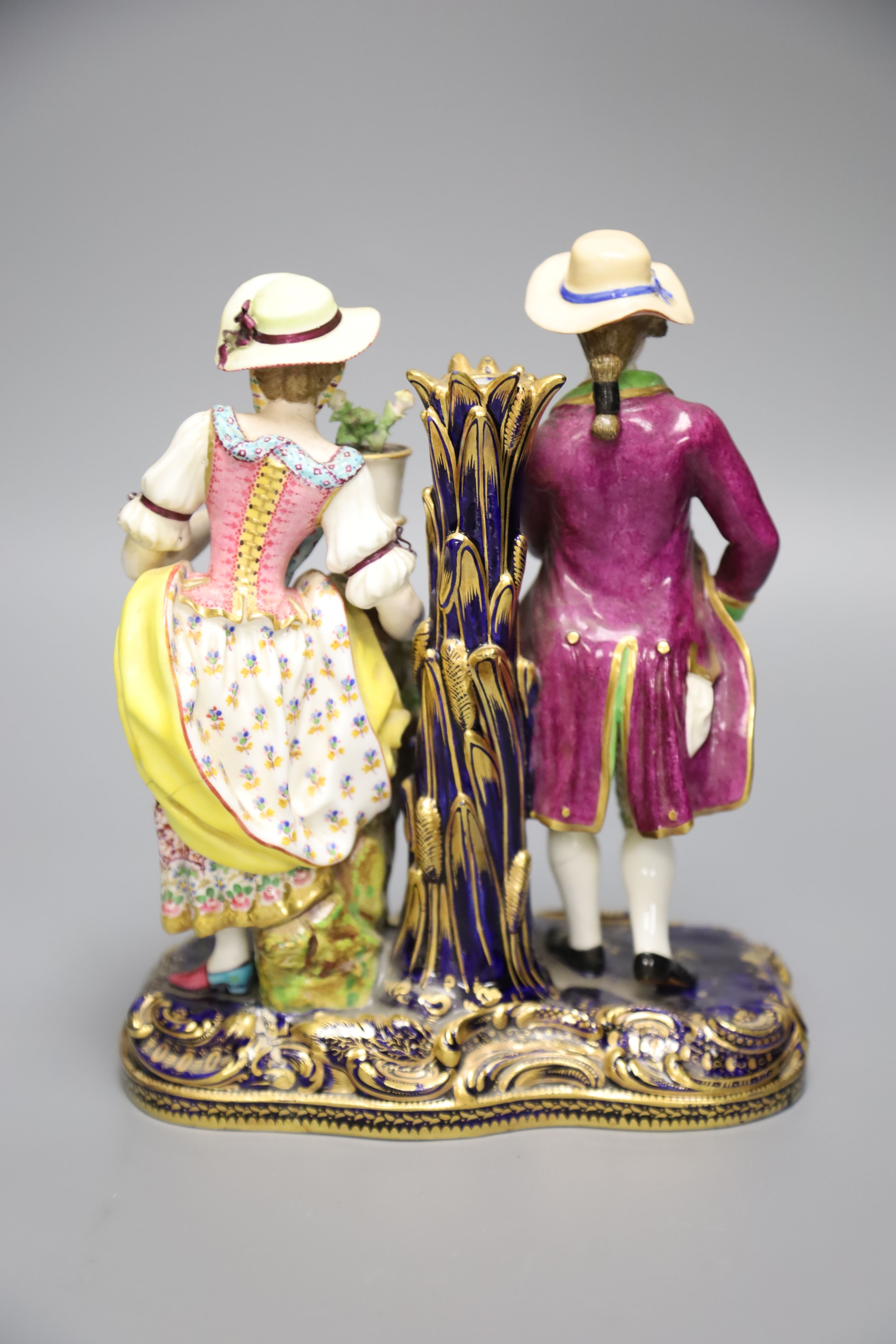 A 19th century Minton figural group and taper stick depicted as a lady and gentleman standing beside a vase of flowers, height 20cm